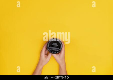 Frau kaukasisch mit Kaffee zum Mitnehmen mit schwarzem Deckel auf gelbem Hintergrund. Stockfoto