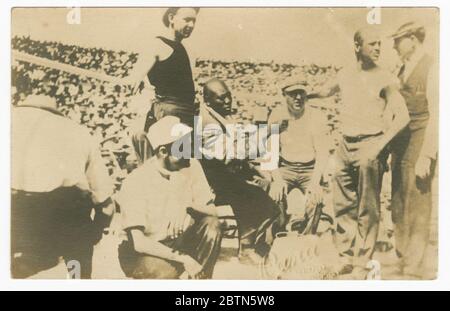 Fotopostkarte von Jack Johnsons Ecke des Rings. Eine schwarz-weiße Fotopostkarte von Jack Johnsons Ecke vor dem 'Kampf des Jahrhunderts' zwischen Johnson und James J. Jeffries. Johnson, sitzend trägt eine Robe und zeigt mit seiner rechten Hand. Er ist von Ausbildungs- und Supportmitarbeitern umgeben. Stockfoto