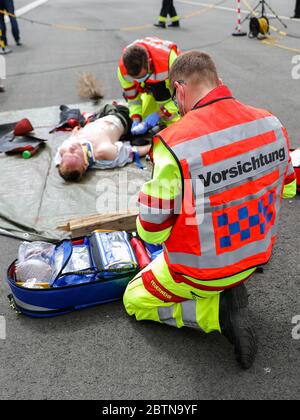 27. Mai 2020, Sachsen, Leipzig: Ein Sanitäter mit "Vorsicht" auf dem Rücken behandelt eine verletzte Person während einer Übung. Während der Übung wurde eine spezielle Tasche für sogenannte "Massenunfall- und Krankheitsfälle" (MANV) vorgestellt. Es enthält unter anderem spezielle Verbandbinden zur Blutungsunterbindung bei schweren äußeren und inneren Verletzungen sowie Markierungen für Menschen mit unterschiedlichem Schweregrad. Bei einem Massenunfall sind zunächst nur wenige Rettungsteams mit einer großen Anzahl von Verletzten konfrontiert. Das Überleben von möglichst vielen Patienten kann durch gewährleistet werden Stockfoto