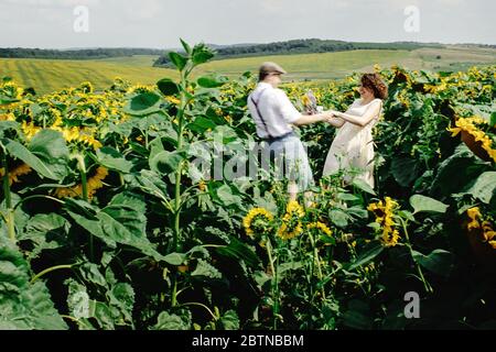 Schöne wunderschöne Braut und stilvolle schönen Bräutigam, fröhliche rustikale Paar in einem Sonnenblumenfeld Stockfoto