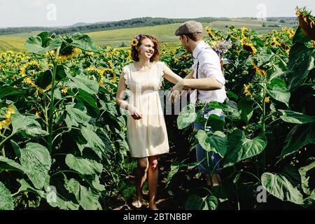 Schöne wunderschöne Braut und stilvolle schönen Bräutigam, fröhliche rustikale Paar in einem Sonnenblumenfeld Stockfoto