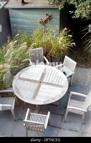 Gartentisch und Stühle aus Holz in einem kleinen modernen Stadtgarten auf Terrasse mit Gräsern und Schuppen Stockfoto
