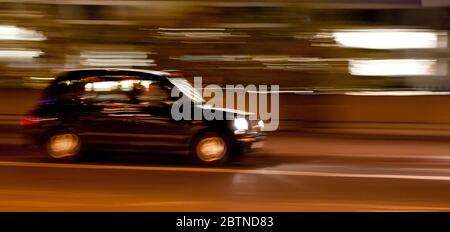 Ein Londoner Taxi in der Nacht mit Bewegungsunschärfe und leichten Streifen Stockfoto