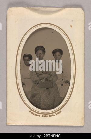 TinType in einem Papierkoffer von drei nicht identifizierten jungen Frauen sitzen. Dieser Weißtyp (A) zeigt drei (3) nicht identifizierte junge Frauen, die sitzen und der Kamera zugewandt sind. Die Frau in der Mitte ist etwas vor den anderen beiden. Sie trägt ein dunkelfarbenes Kleid mit einem helleren Druckmuster und einem spitzen weißen Kragen. Stockfoto