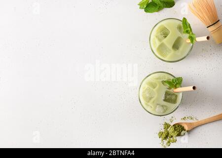 Zwei Gläser eisgrüner Matcha-Tee in Glas auf weißem Hintergrund. Platz für Text. Blick von oben. Horizontale Ausrichtung. Stockfoto