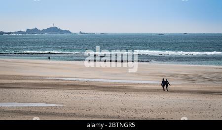 Ein belebender Spaziergang am Strand von St Ouen's Bay, Jersey Channel Islands mit Blick auf den Leuchtturm von La Corbiere Stockfoto