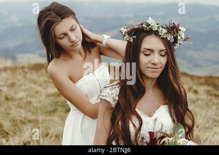 Stilvolle Brautjungfer helfen wunderschöne Braut Vorbereitung, Boho Hochzeit, Luxus-Zeremonie in den Bergen Stockfoto