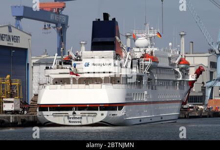 Rostock, Deutschland. Mai 2020. Das Expeditionsschiff "Bremen" legt in der Hansestadt an. Dies ist das erste Mal, dass ein Kreuzfahrtschiff in diesem Jahr festgemacht hat. Auf der rechten Seite sehen Sie ein Ausflugsschiff auf Hafenrundfahrt. An Bord des Schiffes der Reederei Hapag-Lloyd Cruises sind jedoch keine Passagiere, sondern 71 Besatzungsmitglieder. Das Schiff wird zunächst am Maritim Pier im Kreis Groß-Klein vertäut, bevor es seine nächste reguläre Reise mit maximal 155 Passagieren antritt. Quelle: Bernd Wüstneck/dpa-Zentralbild/dpa/Alamy Live News Stockfoto