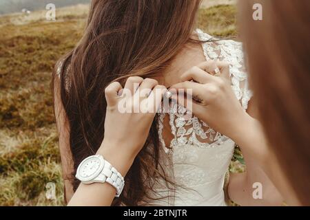 Stilvolle Brautjungfer helfen wunderschöne Braut Vorbereitung, Boho Hochzeit, Luxus-Zeremonie in den Bergen Stockfoto