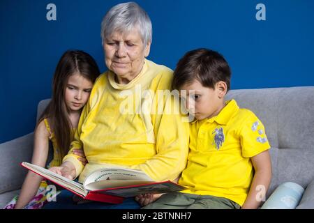 Eine alte Großmutter und ihre geliebten Enkelkinder sitzen zu Hause und fotografieren auf ihrem Smartphone Stockfoto