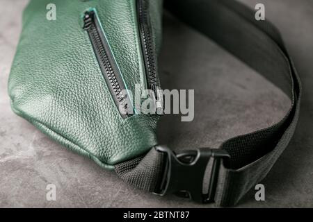 Gürteltasche aus dunkelgrünem Strukturleder, Banane auf grauem Hintergrund. Stockfoto