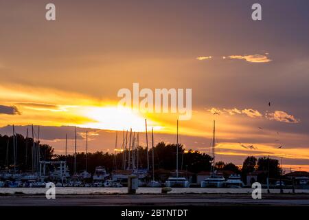 PORTO LAGOS, GRIECHENLAND - 29. NOVEMBER 2019: Die Sonne geht über den Yachten und Booten, die anlegen, schön unter. Orangefarbener goldener Sonnenuntergang über dem Hafen von Porto Lagos, Region Xanthi, Nordgriechenland Stockfoto