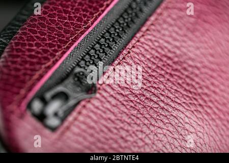 Reißverschluss-Slider für eine Tasche aus strukturiertem rotem Leder. Stockfoto
