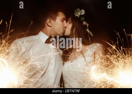 Glücklich schöne Braut und eleganten stilvollen Bräutigam hält Feuerwerk auf der Spitze eines Berges am Abend Stockfoto