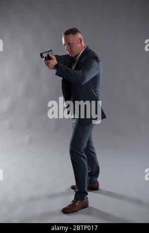 Bild eines weißen, männlichen, verdeckten Polizisten mit einer Pistole auf einem schlichten Hintergrund. Ideal für einen Action-Thriller, Krimi-Thriller Buch oder eBook Cover Design. Stockfoto