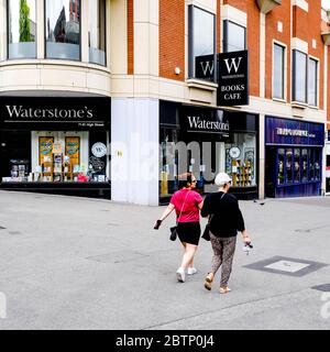 Zwei anonyme Frauen gehen während der Coronavirus-Lockdown an EINEM geschlossenen Waterstone’s Book Shop in South London vorbei Stockfoto