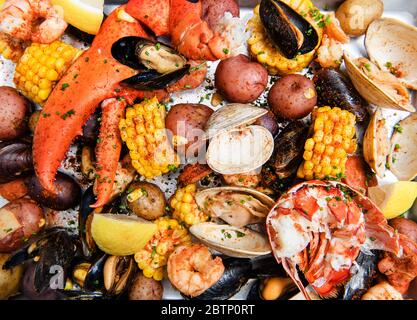 Venusmuscheln backen mit Venusmuscheln, Krabbenbeinen, Hummerkrallen, Muscheln, Kartoffeln, Mais und Gewürzen Stockfoto