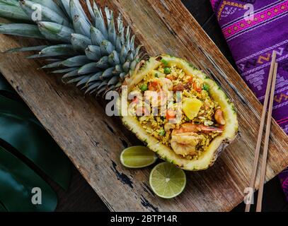 Ananas gebratener Reis mit Garnelen. Serviert in einer Ananas mit Limettengarnitur Stockfoto