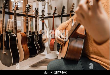 Musikerin die Wahl der neuen Gitarre im Musikinstrumentengeschäft, Kauf eines neuen Musikinstruments Stockfoto