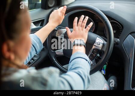 Junge aggressive Fahrerin mit Horn oder Trompeten zu den anderen Autos, gefährliche Fahrer Stockfoto