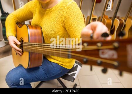 Musikerin die Wahl der neuen Gitarre im Musikinstrumentengeschäft, Kauf eines neuen Musikinstruments Stockfoto