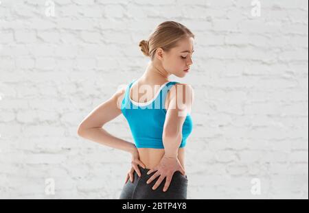 Attraktive junge Frau, die an sportbedingten Rückenschmerzen im Fitnessstudio leidet Stockfoto