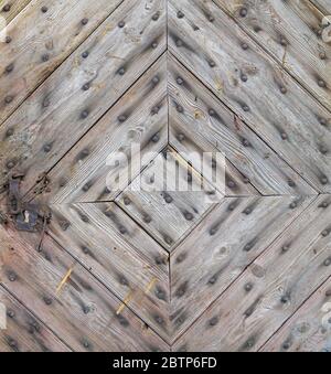 Die Tür des alten Landhauses besteht aus diagonalen Brettern und rostigen Nägeln. Das Holz rissig aus dem Alter. Stockfoto