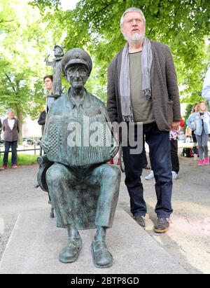 Rostock, Deutschland. Mai 2020. Nach der Enthüllung des Denkmals für den 'Instrel-Großvater' Michael Tryanowski (1919-2018) steht Wolfgang Friedrich, Bildhauer, neben seiner Skulptur am Universitätsplatz. Das Rostocker Original Michael Tryanowski wurde zu seinem 95. Geburtstag am 12.12.2014 mit einem Eintrag in das Ehrenbuch der Hanse- und Universitätsstadt Rostock geehrt. Quelle: Bernd Wüstneck/dpa-Zentralbild/ZB/dpa/Alamy Live News Stockfoto