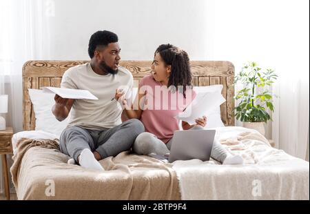 Verheiratetes Paar streiten, während die Finanzen im Schlafzimmer überprüft werden Stockfoto