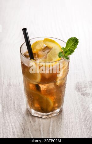 Eistee-Drink mit Zitrone im Glas auf weißem Holztisch Stockfoto