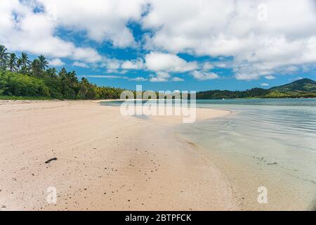 Weitwinkel Blick auf einen weißen Sandstrand, tropische Inseln eine Palme in der Ferne.mit einem schönen Himmel von Wolken. Yasawa Fiji Stockfoto