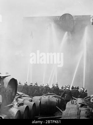 London Rennen Lager Flammen . Carbett ' s Reis Lager in Shad Thames Feuer gefangen und brannte wütend. Foto zeigt, Feuerwehrleute Leitung Schläuche auf das lodernde Gebäude. April 1936 Stockfoto