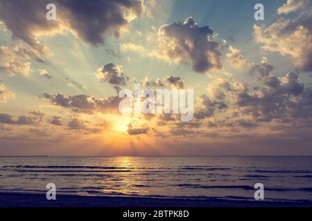 Wunderbarer Sonnenaufgang über dem Meer mit goldener Sonne, Wolken und Lichtstrahlen Stockfoto
