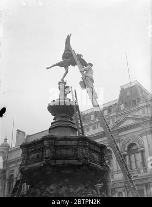 Eros hellte sich auf für Krönung. Sie sind in einem Arbeiter, der der Eros-Statue im Piccadilly Circus eine 'Bürstenarbeit' gibt, damit er die Krönungsscharen herzlich willkommen heißt. 16. April 1937 Stockfoto