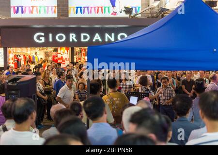 Hongkong / China - 26. Juli 2015: Straßenmusiker treten in Kowloon, Hongkong, vor einer großen Menge von Zuschauern auf Stockfoto