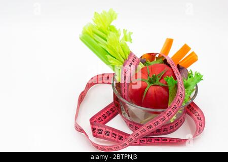 Konzept der Gewichtsverlust, Gemüse mit rosa Maßband auf weißem Hintergrund. Nahaufnahme. Platz für Text Stockfoto