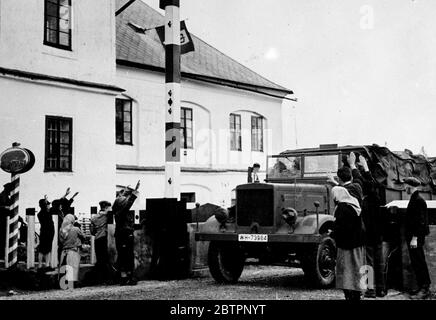 Deutsche marschierten in die Tschechoslowakei ein, erste Originalbilder erreichten London. Dies sind die ersten Originalbilder, die London von der Besetzung der Sudetengebiete der Tschechoslowakei durch Hitlers Armeen erreichten. Speziell gecharterte Flugzeuge und eine Autofahrt von mehr als 200 Meilen waren daran beteiligt, diese Bilder nach England zu bringen. Foto zeigt, wie der Schwerlastwagen der deutschen Armee während der Besatzung die erhöhte Zollschranke und Häuser in Kleinphillipareut an der Grenze passiert, als Dorfbewohner den Nazi-Gruß geben. Oktober 1938 Stockfoto