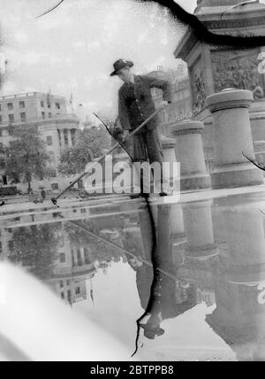 Es ist feucht unter den Füßen in London. Ein Kehrmaschine spiegelte sich in der glitzernden Oberfläche des Trafalgar Square wider, als er nach Londons starkem Regen den nassen Bürgersteig quietschte. Juli 1938 Stockfoto