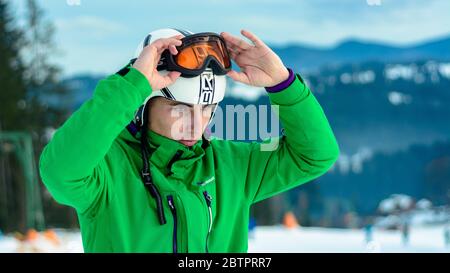 Ein Mann Skifahrer trägt einen Helm briko und Skibrille Schwäne vor dem Training für die Sicherheit. Ein professioneller Snowboarder bereitet sich auf Wettkämpfe 2021 vor. Yablun Stockfoto