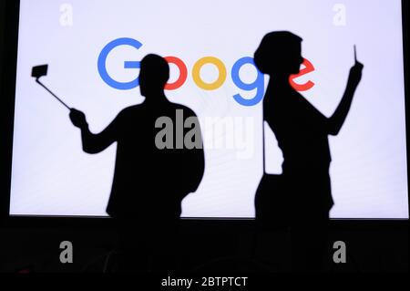 NEW YORK, USA, 25. MAI 2020: Google Unternehmen für Internet-Interessen. Paar, die ein Foto auf einem mobilen Mann verwenden einen Selfie-Stick. Firmenlogo auf Bildschirm i Stockfoto