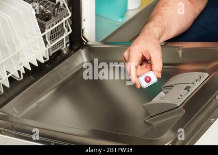 Mann, der eine Waschmitteltablette in die Spülmaschine stellt Stockfoto