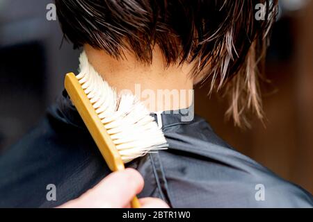 Hand os Friseur ist Reinigung Hals mit Pinsel von geschnittenen Haaren nach dem Haarschnitt. Stockfoto