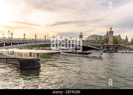 Ein Touristenboot, das zur goldenen Stunde unter der Brücke Pont Alexandre III in Paris vorbeifährt Stockfoto