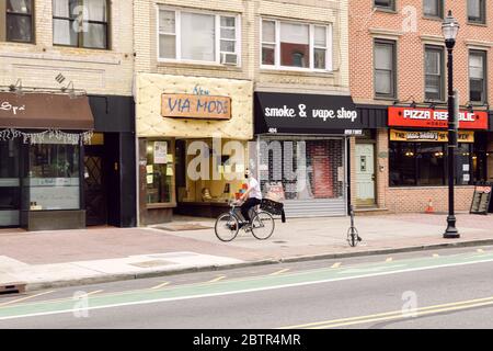 April 20 2020 - Hoboken NJ: Eine Person, die auf einer leeren Straße mit dem Fahrrad in einer Maske fährt Stockfoto