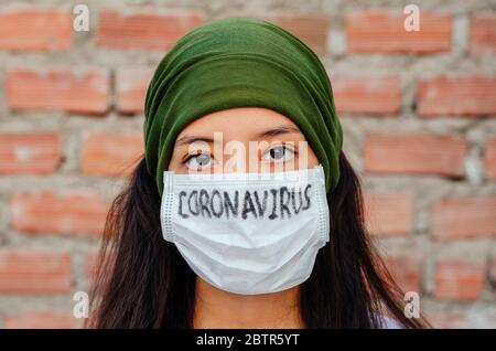 Mädchen mit Maske, um sich vor dem Coronavirus zu schützen. Covid-19-Pandemie. Coronavirus in Maske geschrieben Stockfoto