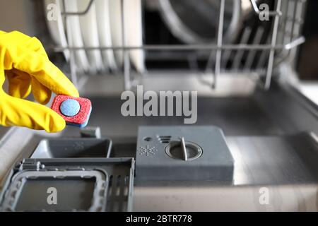 Handschuhen, die das Spültablett in der Spülmaschine halten Stockfoto