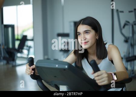 Fit junge Mädchen mit Heimtrainer im Fitnessstudio. Fitness-Frau mit Air Bike im Fitnessstudio. Stockfoto