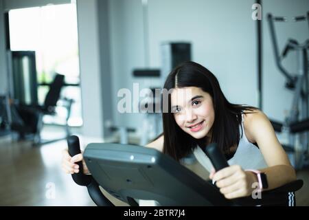 Fit junge Mädchen mit Heimtrainer im Fitnessstudio. Fitness-Frau mit Air Bike im Fitnessstudio. Stockfoto