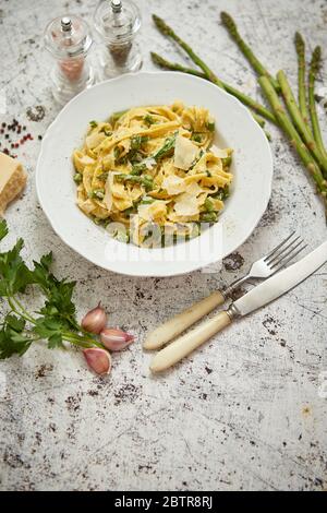 Tagliatelle Pasta mit cremiger Ricotta-Käsesoße und Spargel serviert weiße Keramikplatte Stockfoto