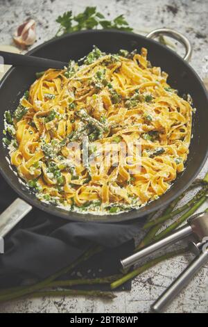 Tagliatelle Pasta mit Ricotta-Käsesoße und Spargel auf einer schwarzen Eisenpfanne serviert Stockfoto